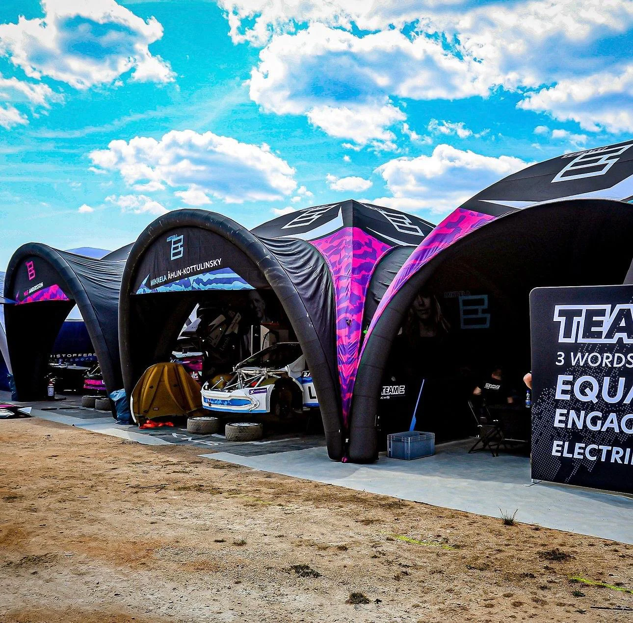 WRX Racing team tents with pink and black branding in the paddock