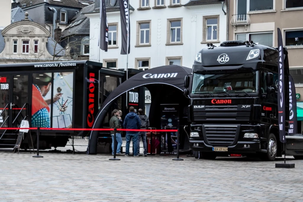 Black branded Airdome next to a truck on a square